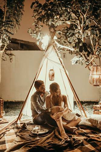 person couple sitting inside tepee hut with lights human