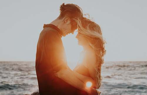 love man and woman hugging near sea during golden hour relationship