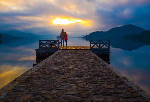 dock couple standing on dock looking at sunset pier