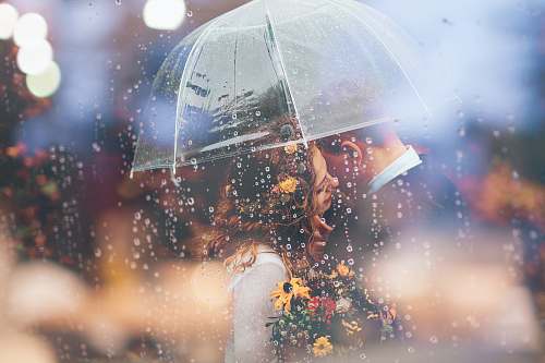 couple a bride and groom kiss in the rain under an umbrella love