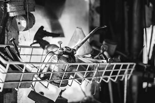 person grayscale photography of oil can on wire rack human