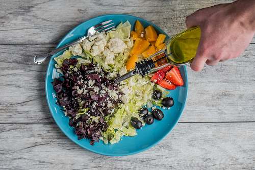 bowl flat lay photography of man making vegetable and fruit salad olive oil