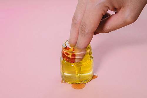 person jar of oil finger