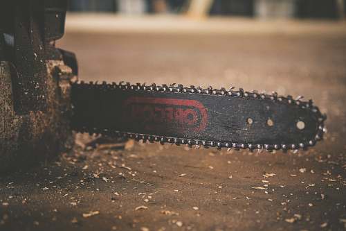 chainsaw black and red Oregon chainsaw on brown wood plank blade
