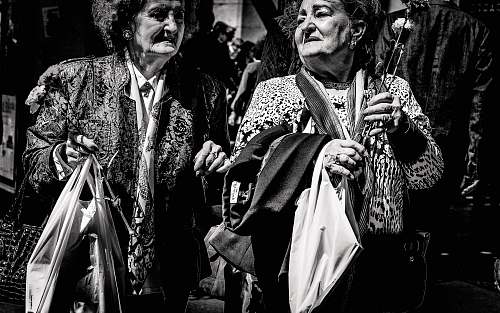 human grayscale photo of two women holding bags person