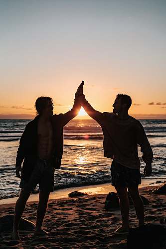 ocean two men clapping each other on shore nature