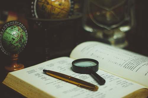 globe click pen and magnifying glass on book page research