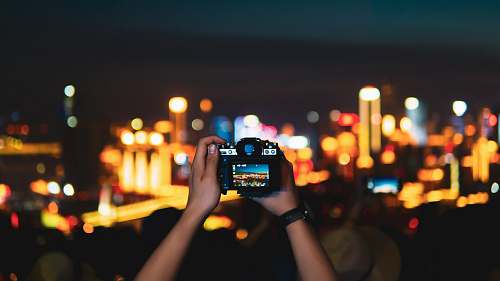 person man taking photo of lighted city skyline at night with DSLR camera human