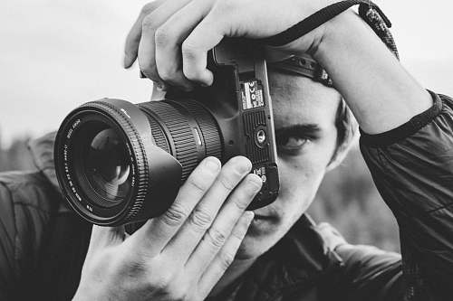 camera man holding DSLR camera black-and-white