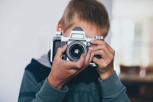 person boy holding gray camera camera