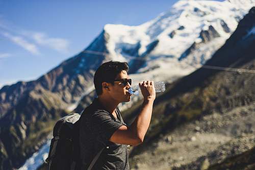 person man drinking water at top of mountain mountain