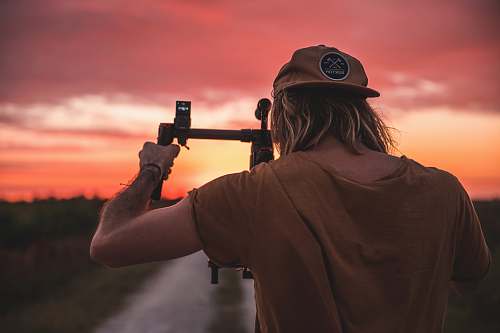 person man holding camera with stabilizer during golden hour apparel