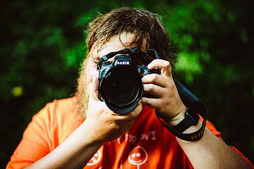 person man holding Nikon camera camera