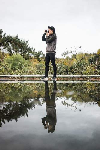 person man standing near body of water using camera photo
