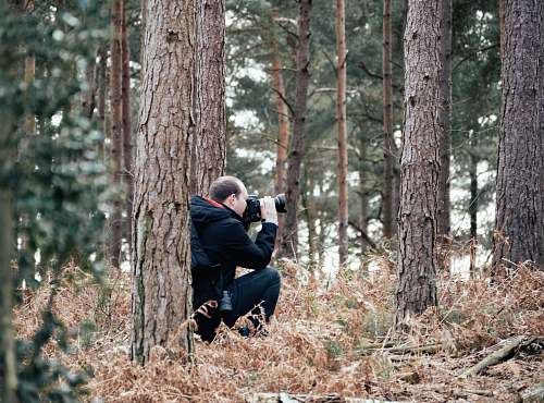 person man taking picture in the woods using a DSLR camera photographer