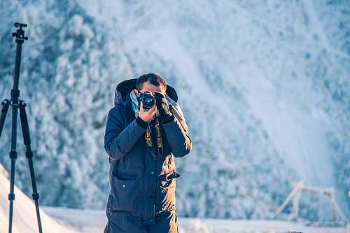 person man wearing black hoodie holding camera photo