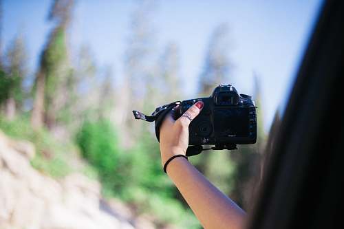 camera person holding DSLR camera electronics