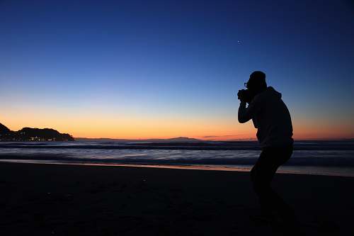 person silhouette of person standing near seashore photo