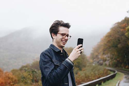 person smiling man looking at his smartphone mobile phone