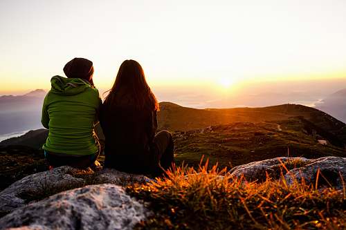 nature two women sitting on rock boulder sunrise