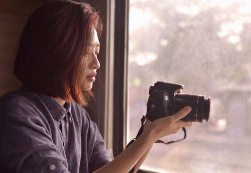 person woman in blue collared shirt holding black DSLR camera camera