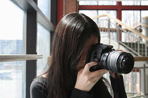 person woman standing near window using DSLR camera camera