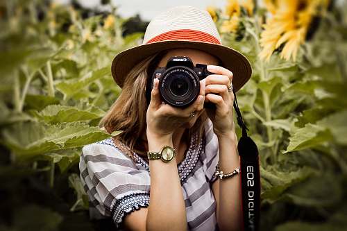 person woman taking photo of plants hat