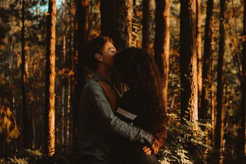 human man kissing woman's forehead in forest tree