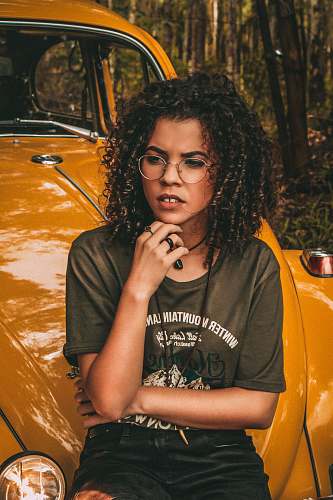 woman woman resting chin sitting on yellow Volkswagen Beetles hood person