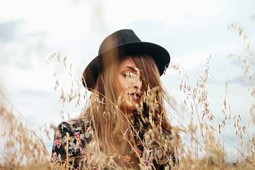 woman woman wearing black hat near brown grass during daytime girl