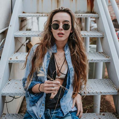 denim woman wearing black sunglasses on stairs woman
