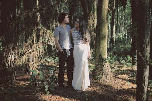 human man and woman standing together surrounded by green trees and plants during daytime people
