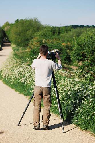 human man in white sweatshirt holding camera tripod