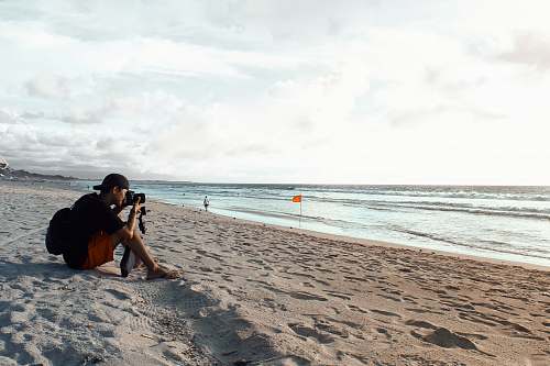 human man sitting on shore photographer
