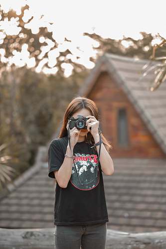 human woman standing and using DSLR camera photo