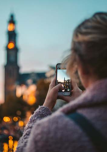 human woman taking photo of a building during daytime phone