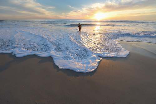 ocean man standing on seashore during sunset water