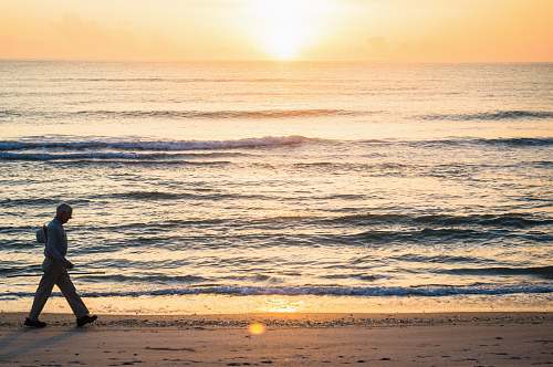 ocean man walking beside ocean at sunset sea