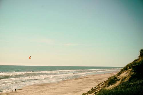 water person flying kite on seashore ocean