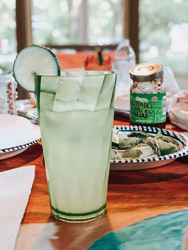 drink lime juice with sliced lime on top near food in plate beside organic chipotle and lime salsa jar on table lemonade