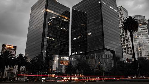 building grayscale photo of two glass buildings near road office building