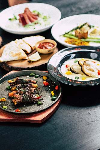 meal cooked food on top of black and white ceramic plates plate