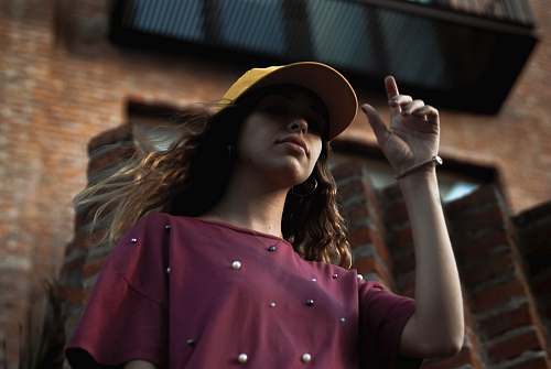 human low angle of woman standing near brick building hat