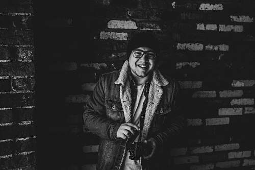 apparel grayscale photography of smiling man carrying camera clothing
