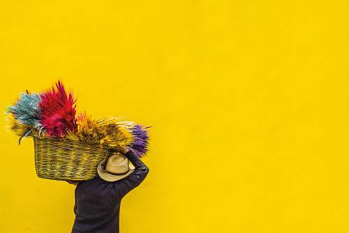 yellow person in black top carrying brown wicker basket guatemala