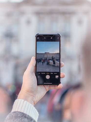 phone person taking photograph of people near fountain at daytime cell phone
