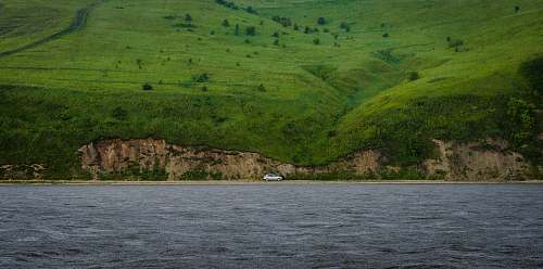 landscape white car travelling on road in middle of hill and sea coast