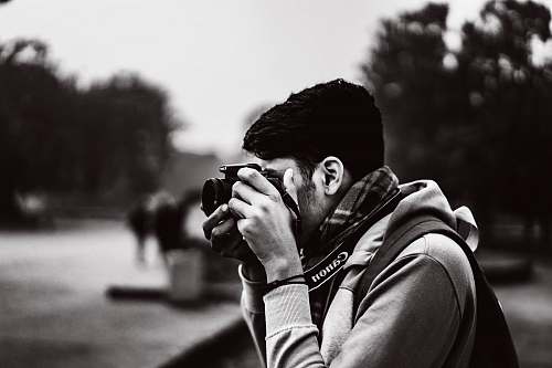 person grayscale photography of man taking photo using camera camera