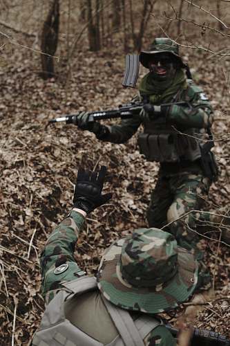 military man holding assault rifle in the middle of forest military uniform