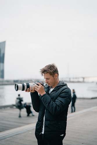 person man holding black DSLR camera outdoors photographer